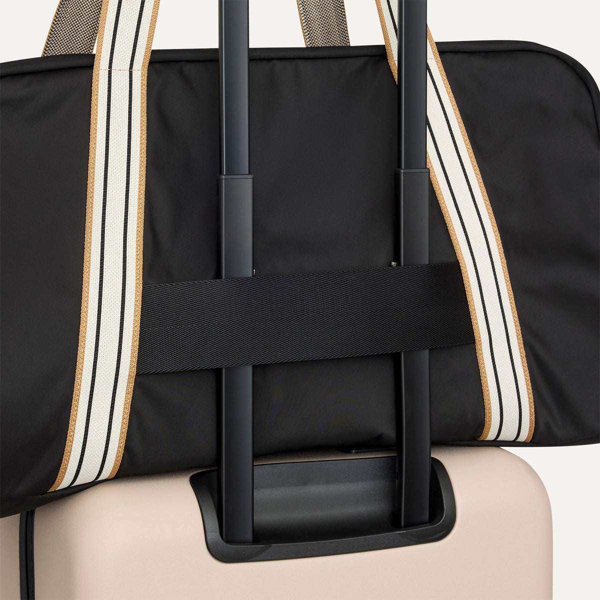 The Travel Duffle in Ink shown attached to a rolling suitcase using the wrap-around band.