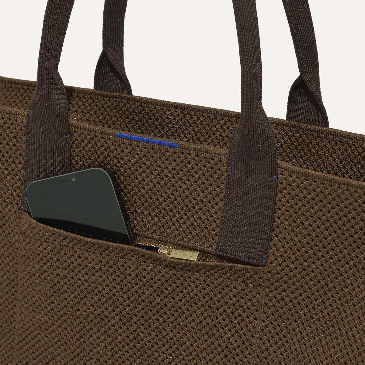 A closeup of The Classic Tote in Cinnamon Open Knit, focusing on the exterior zip pocket.