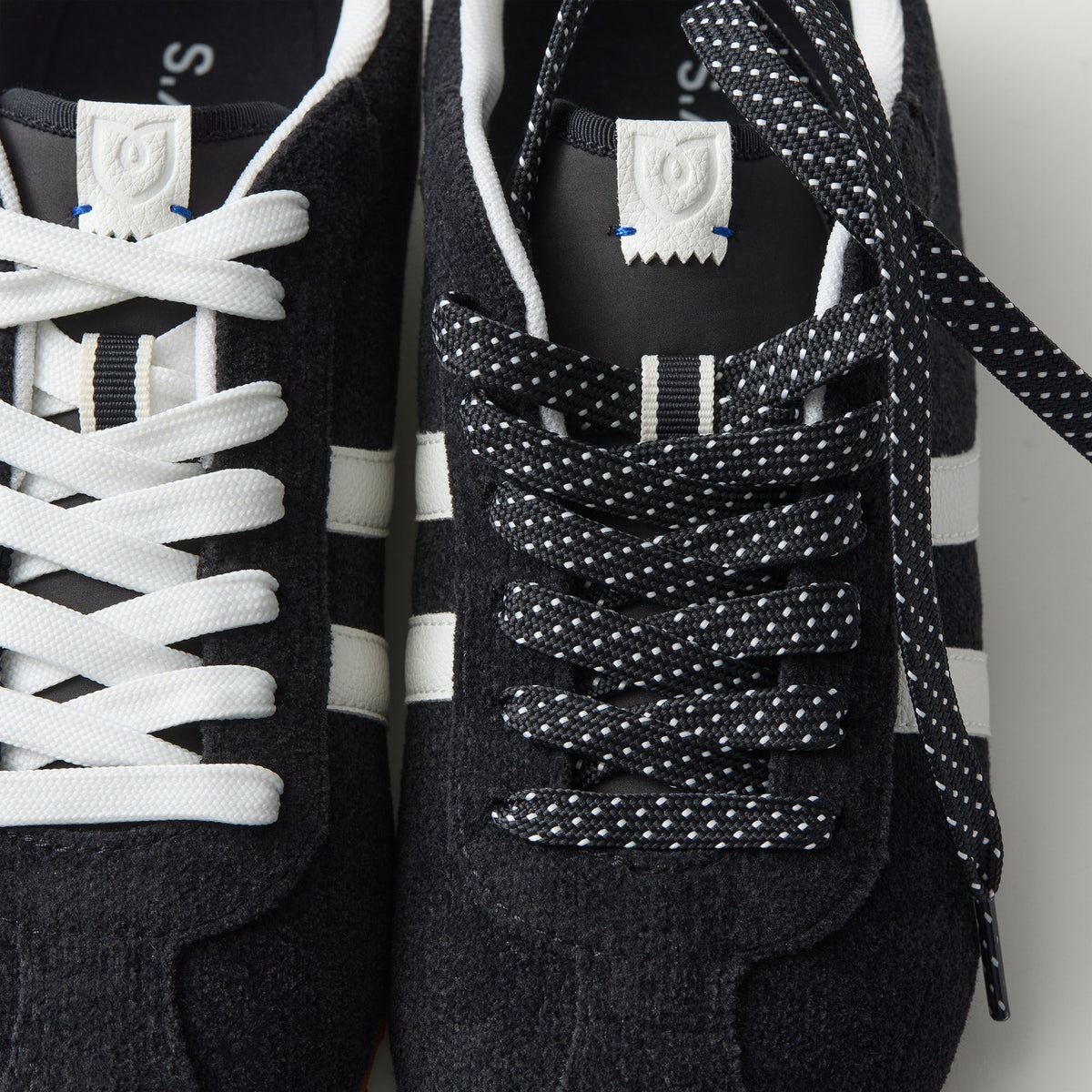 Overlay:: Extra pair of laces included—swap for a new look anytime. | Alt:: Close up of the top of The Ivy Sneaker in ReVelvet Black, showing different lace choices.